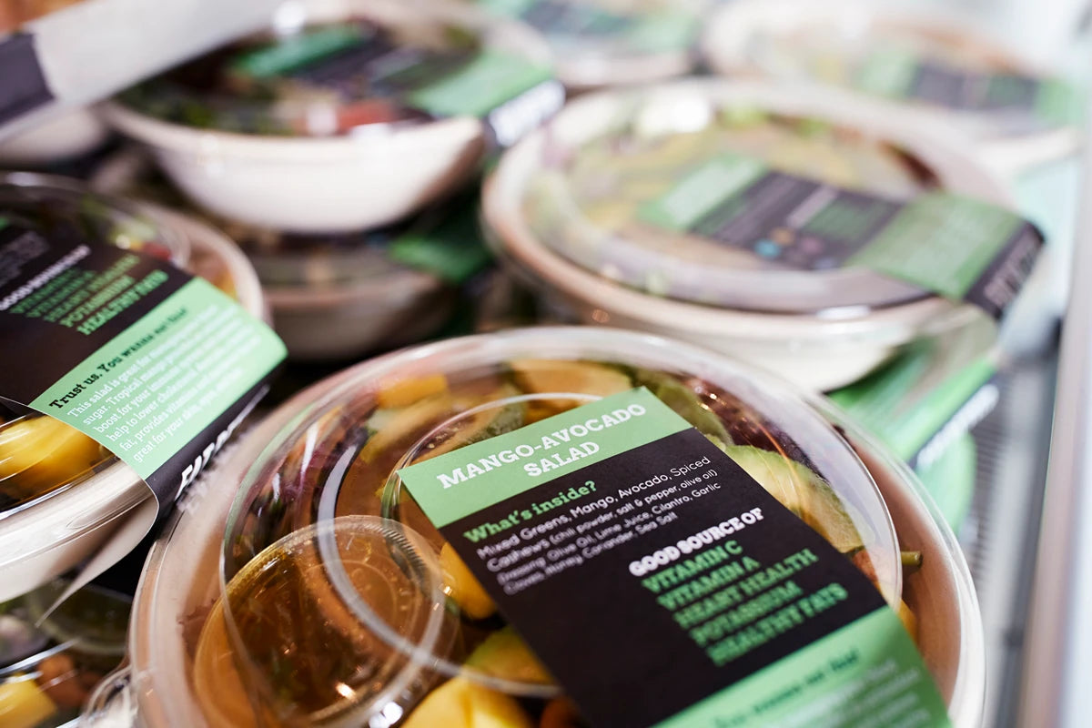 Food production labels on round boxes of mango avocado salad