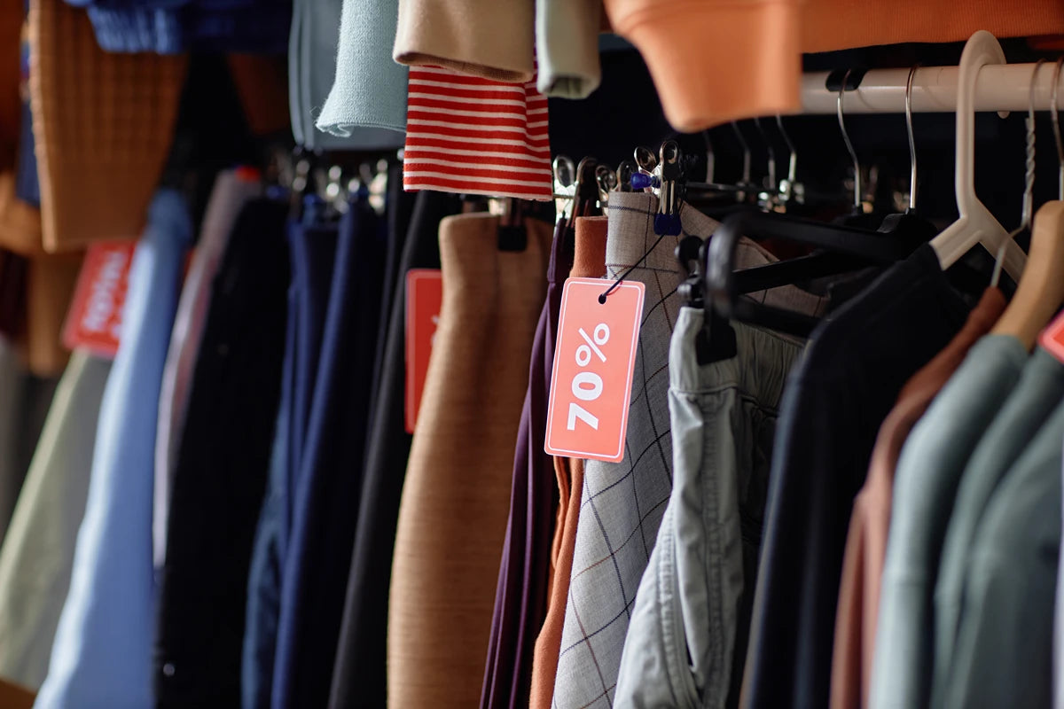 A rack of clothing with retail tags and labels attached