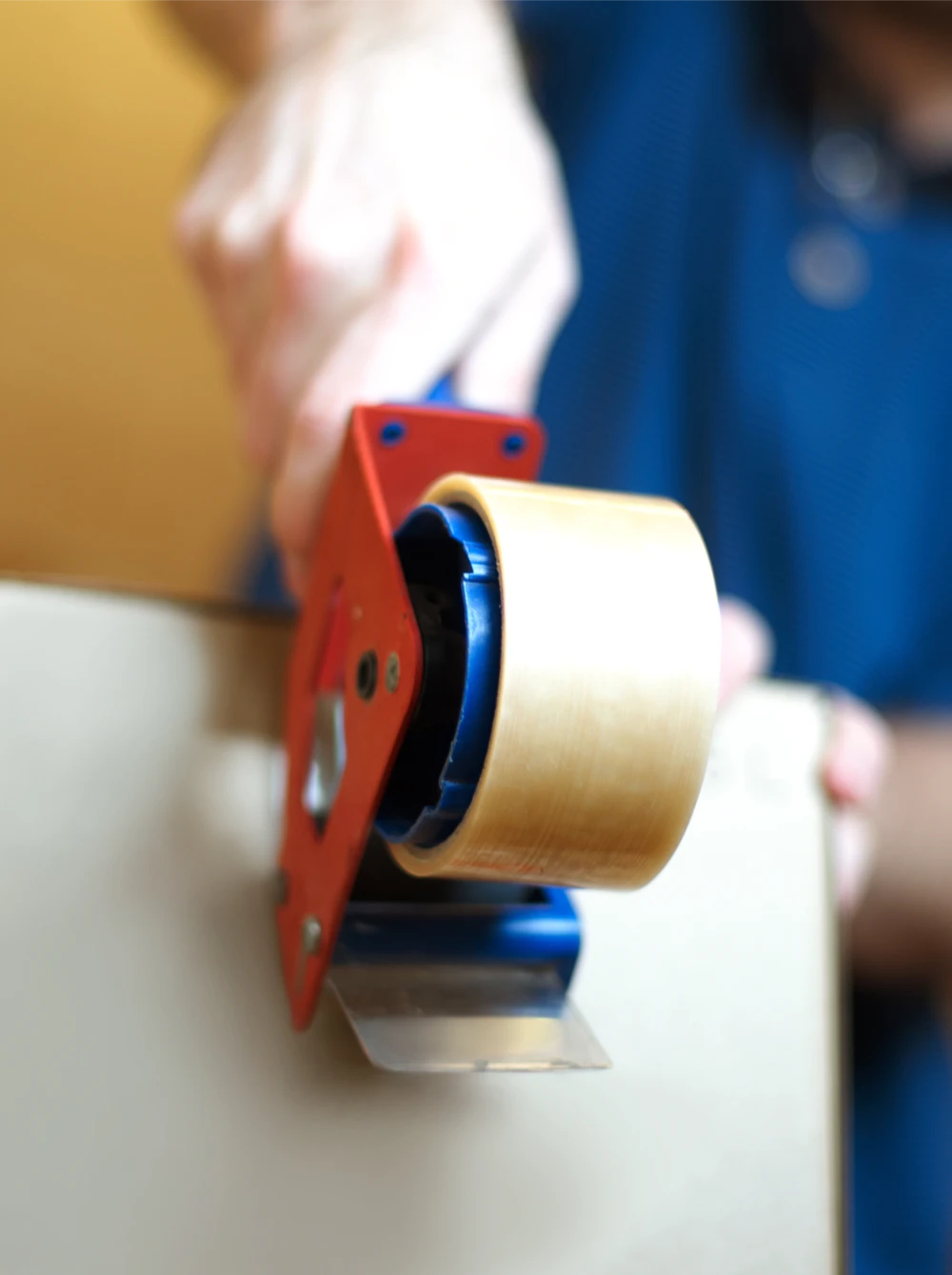 Worker sealing a cardboard box with a handheld tape dispenser